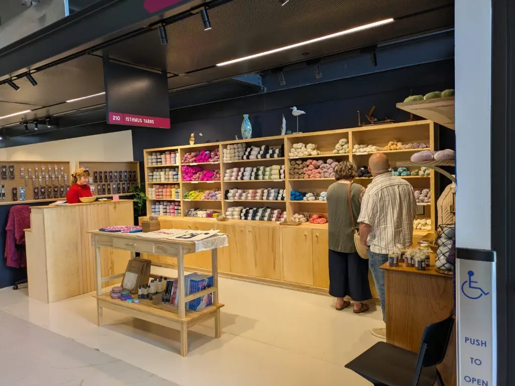 Wide view of a merchant shop interior with wood shelving and a customer browsing products